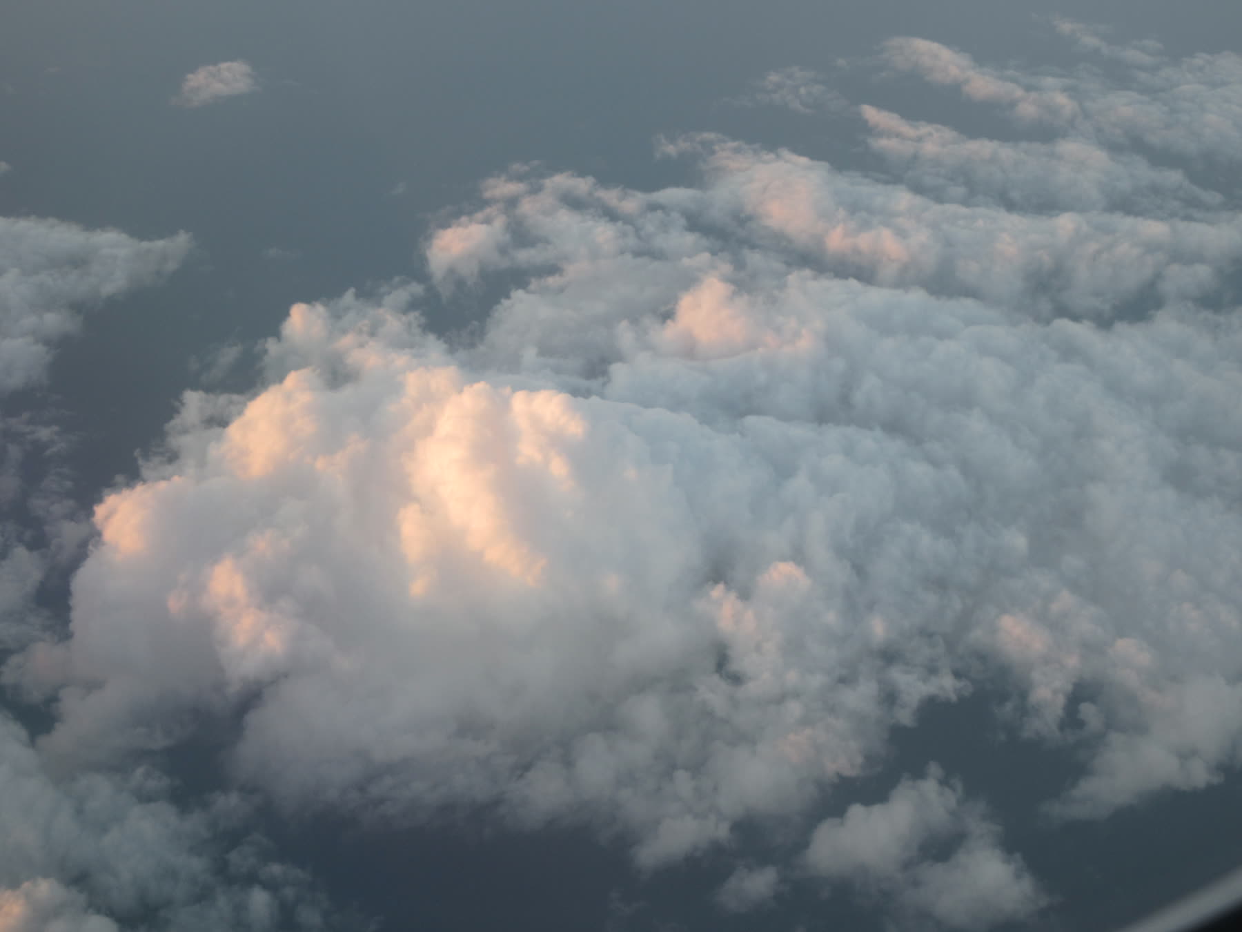 Clouds seen from above with soft peach sunlight falling across them.