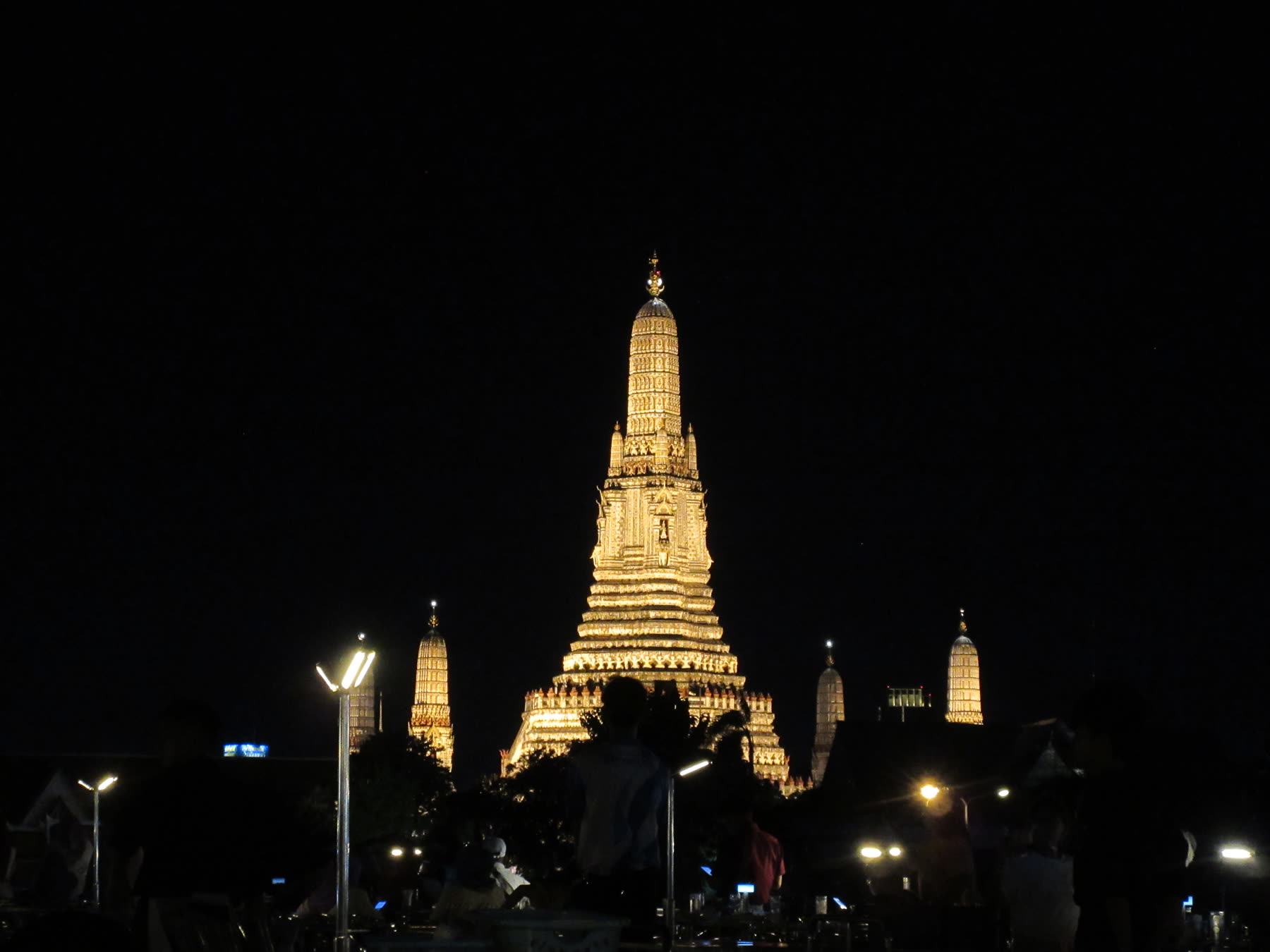 An illuminated temple tower at night against a nearly black sky.